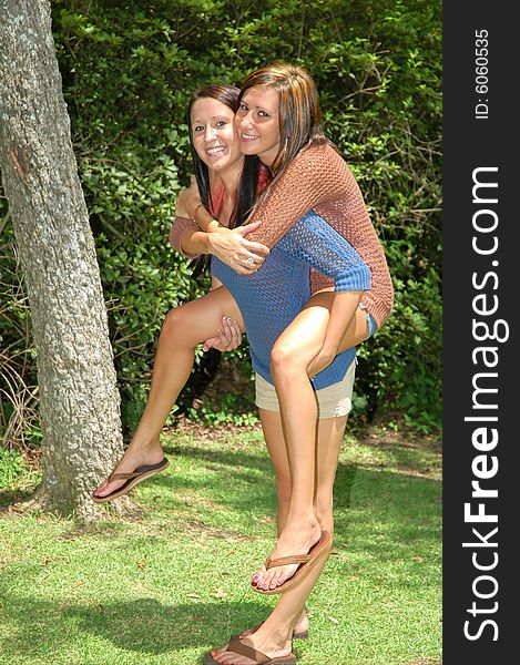 One young lady gives another a piggy back ride. One young lady gives another a piggy back ride.