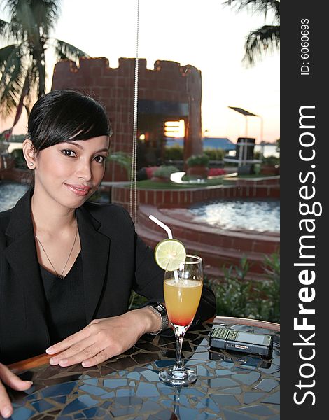 Girl in business suit enjoy cocktail at bar, sunset at background. Girl in business suit enjoy cocktail at bar, sunset at background