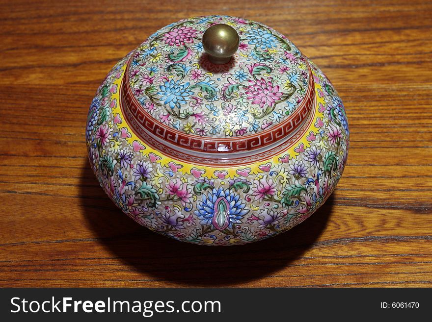 A colorful china jar on wood background.