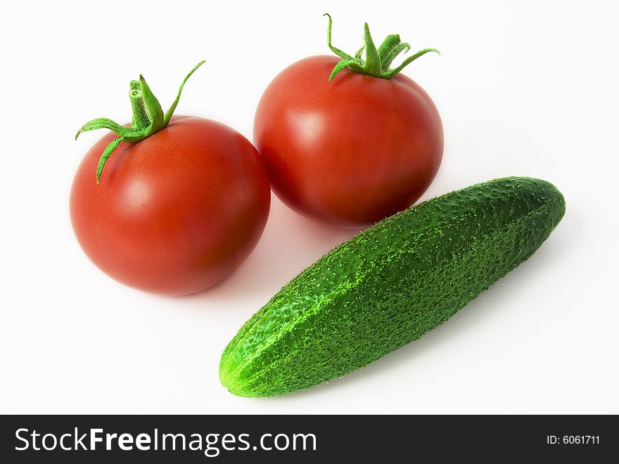 Two ripe tomatoes and cucumber on the white background