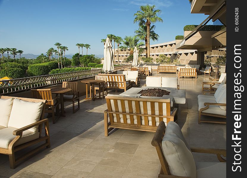 A relaxing balcony with cushioned seats at a resort, overlooking the desert valley and palm trees below. A relaxing balcony with cushioned seats at a resort, overlooking the desert valley and palm trees below