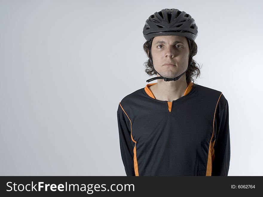 Man wearing a helmet stands with his hands behind his back and has a serious expression on his face.  Horizontally framed photograph. Man wearing a helmet stands with his hands behind his back and has a serious expression on his face.  Horizontally framed photograph