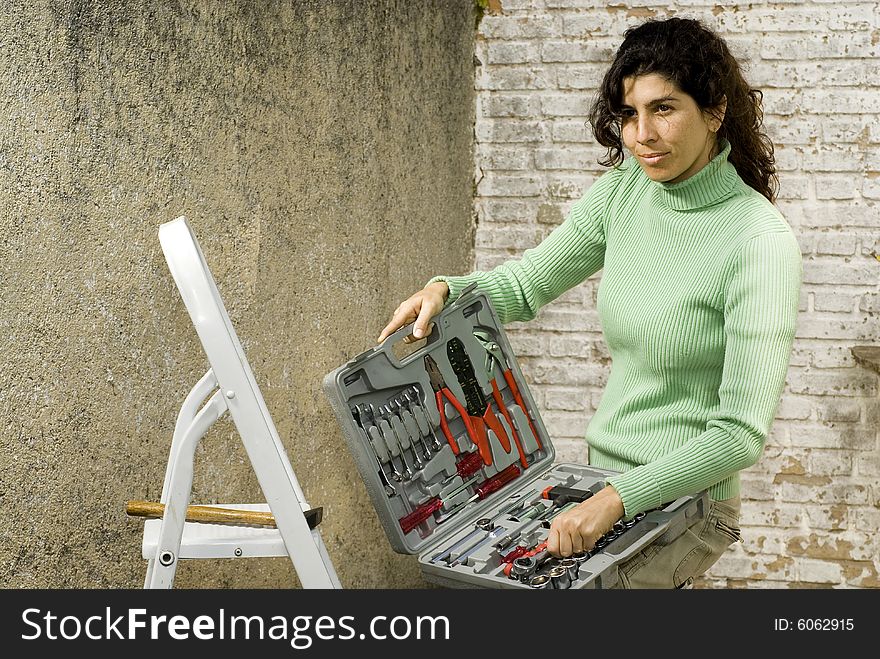 Woman displaying a box of tools with a small smile upon her face. Horizontally framed photo. Woman displaying a box of tools with a small smile upon her face. Horizontally framed photo.