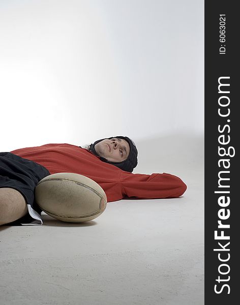 Rugby player lays on the floor with his football.  Vertically framed photograph. Rugby player lays on the floor with his football.  Vertically framed photograph