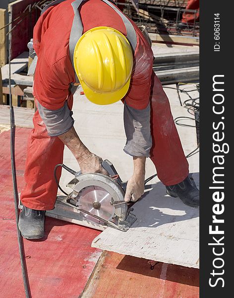 Construction worker bending over to use a rotary saw. Vertically framed photo. Construction worker bending over to use a rotary saw. Vertically framed photo.