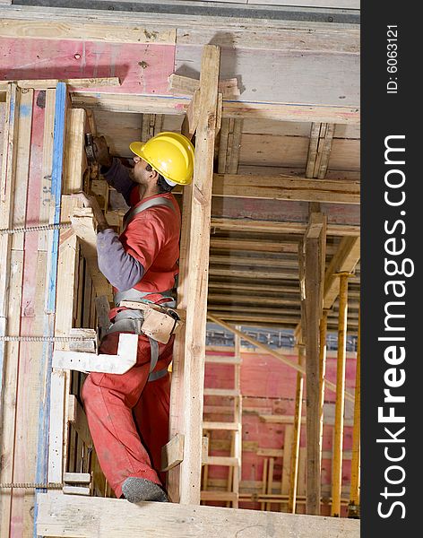 Construction worker installs studs and insulation while building wall. Vertically framed photo. Construction worker installs studs and insulation while building wall. Vertically framed photo.