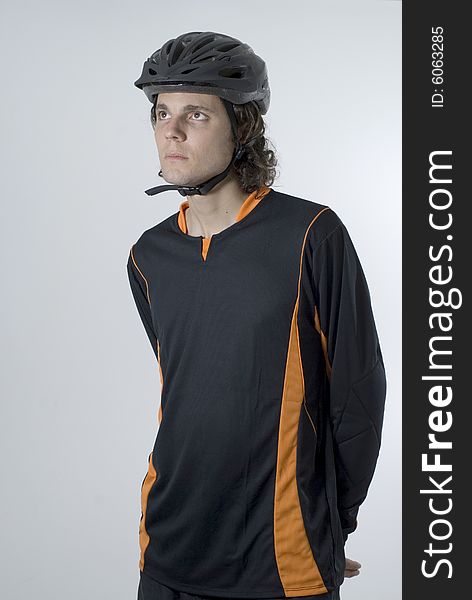 Man wearing a helmet stands with his hands behind his back and has a serious expression on his face.  Vertically framed photograph. Man wearing a helmet stands with his hands behind his back and has a serious expression on his face.  Vertically framed photograph