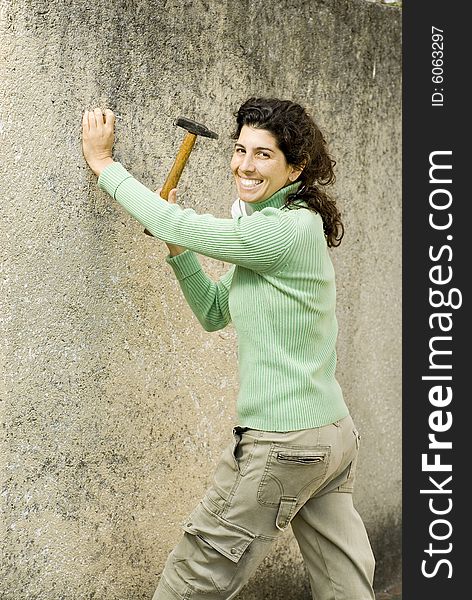 Smiling woman hammering a wall. Vertically framed photo. Smiling woman hammering a wall. Vertically framed photo.