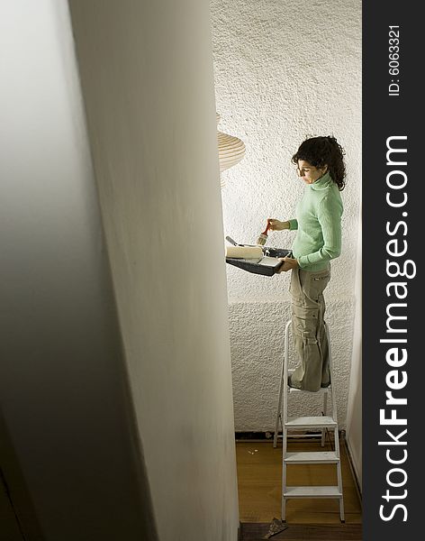 Aerial view of a woman painting a wall - Vertically framed photo. Aerial view of a woman painting a wall - Vertically framed photo.