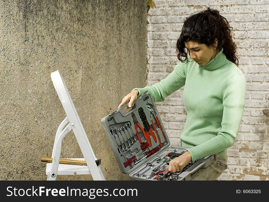 Woman opens toolkit and reviews tools. Horizontally framed photo. Woman opens toolkit and reviews tools. Horizontally framed photo.