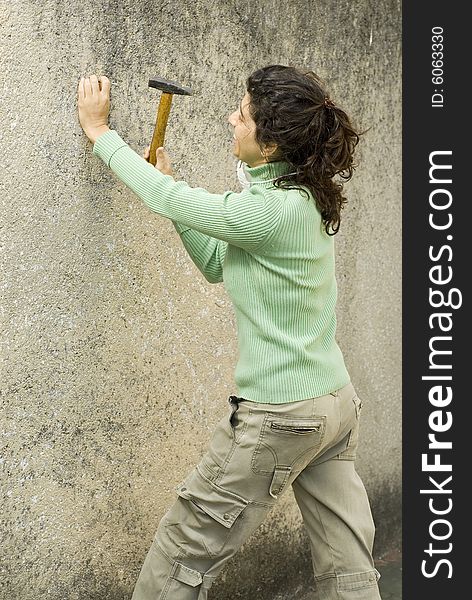 Woman hammering a wall. Vertically framed photo. Woman hammering a wall. Vertically framed photo.