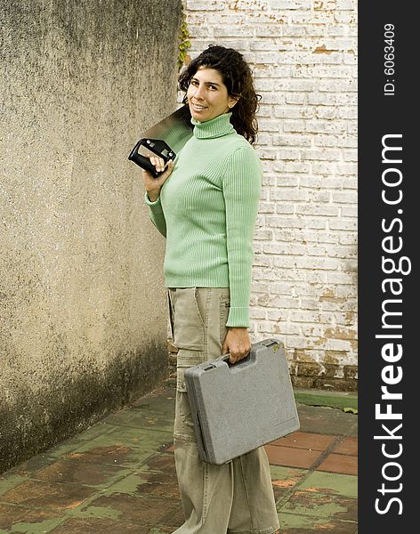 Woman stands in unfinished room holding hand saw and a toolkit. She is looking at the camera. Vertically framed photo. Woman stands in unfinished room holding hand saw and a toolkit. She is looking at the camera. Vertically framed photo.