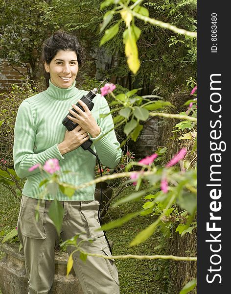 Smiling woman holding a drill by some flowers. Vertically framed photo. Smiling woman holding a drill by some flowers. Vertically framed photo.