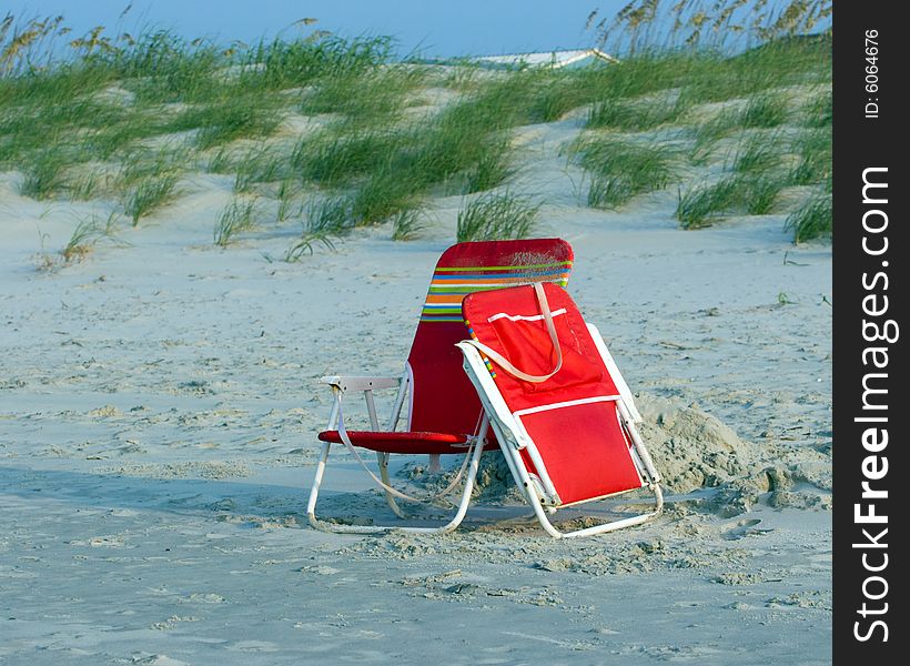 Multi-colored beach chairs on the sand in front of the dunes