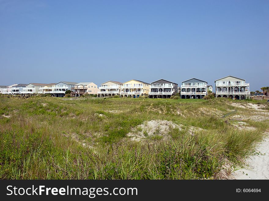 Row of beach houses across the green sand dunes