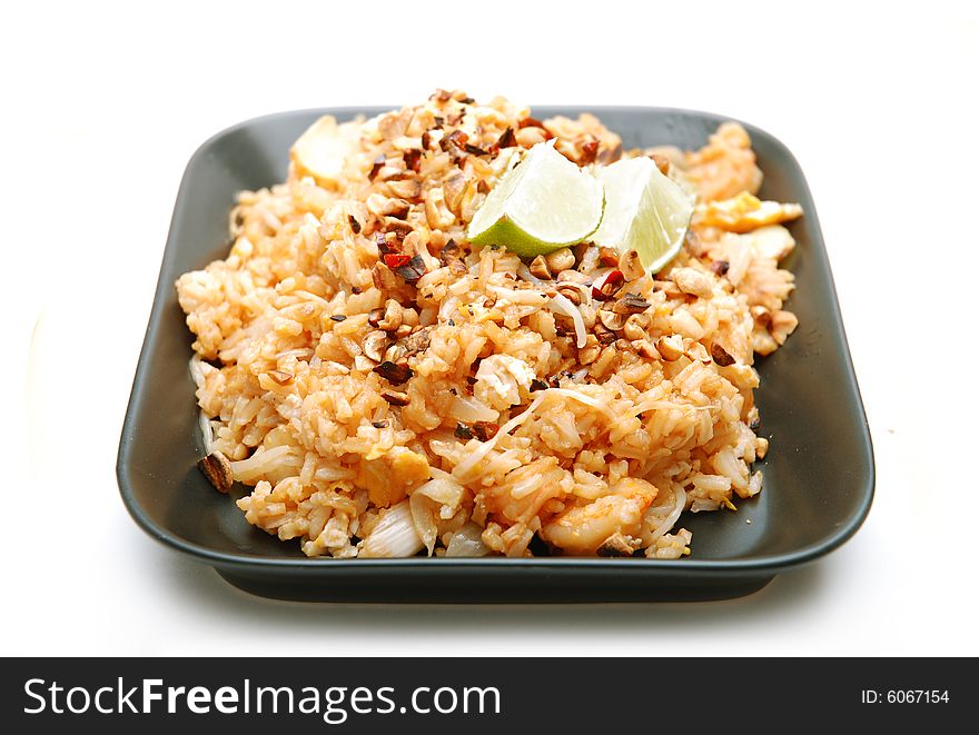 Asian rice dish served on black plate, isolated on white background.