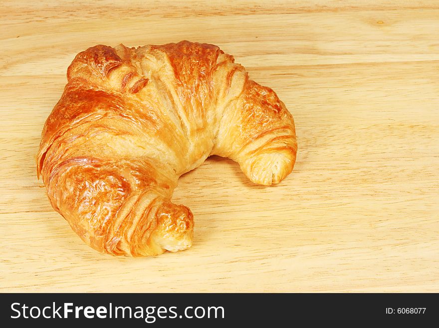 Single croissant on a bread board. Single croissant on a bread board