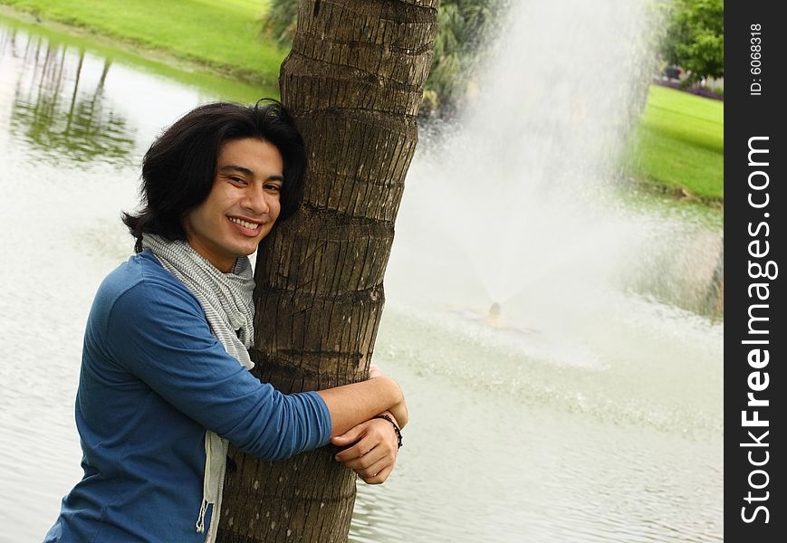 Young man smiling and hugging a tree. Young man smiling and hugging a tree.