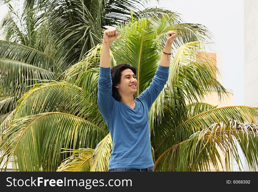 Young man raising his arms in the air as a victorious gesture. Young man raising his arms in the air as a victorious gesture