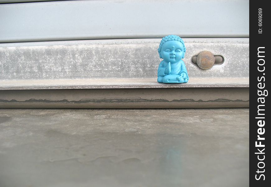 Little blue buddha figurine on a window sill. Horizontally framed photo. Little blue buddha figurine on a window sill. Horizontally framed photo.