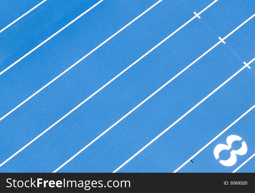 A photograph the lanes of a blue, quarter mile race track from above