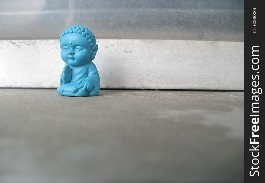 Little blue buddha statue on a sidewalk. Horizontally framed photo. Little blue buddha statue on a sidewalk. Horizontally framed photo.