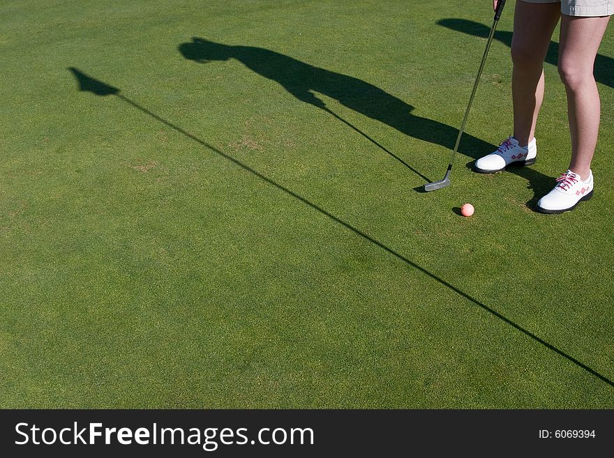 Golfer's shadow shows him putting on golf green. Horizontally framed photo. Golfer's shadow shows him putting on golf green. Horizontally framed photo.