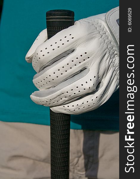 Golfer's gloved hand holds golf club. Vertically framed photo. Golfer's gloved hand holds golf club. Vertically framed photo.