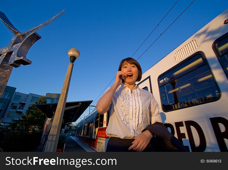 Woman on cellphone looks surprised. She is standing next to a train. Horizontally framed photo. Woman on cellphone looks surprised. She is standing next to a train. Horizontally framed photo.