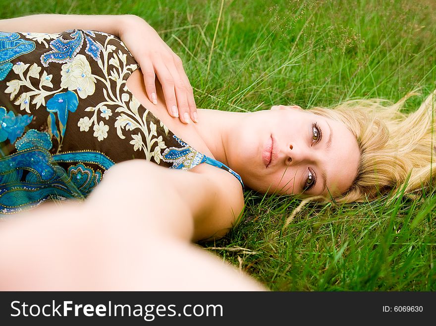 Young beautiful blond girl laying down on the green grass. Young beautiful blond girl laying down on the green grass