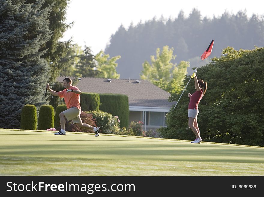 Couple playing golf celebrating a great putt. Horizontally framed shot. Couple playing golf celebrating a great putt. Horizontally framed shot.