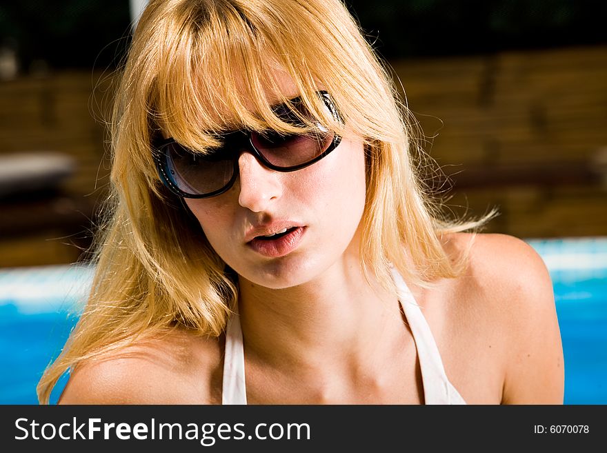 Young blond girl enjoying the sun in and around the swimming pool. Young blond girl enjoying the sun in and around the swimming pool