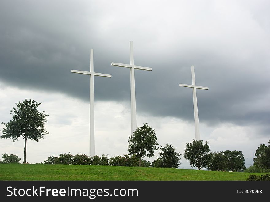 Three (3) huge white crosses on a hill against a cloudy sky. Three (3) huge white crosses on a hill against a cloudy sky