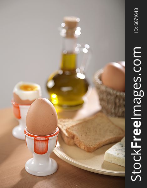 Breakfast table with toast bread and boiled eggs in cups in blur with windows reflections in the background. Breakfast table with toast bread and boiled eggs in cups in blur with windows reflections in the background.