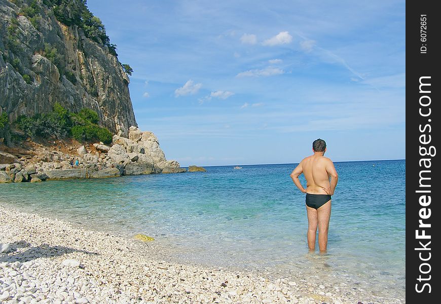 Middle-aged man standing in water of a beautiful beach *with space for text (copyspace). Middle-aged man standing in water of a beautiful beach *with space for text (copyspace)