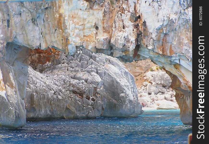 Cala Goloritze in Sardinia - Italy detail: view of beautiful stretch of white pebbles through natural arch the sea. Cala Goloritze in Sardinia - Italy detail: view of beautiful stretch of white pebbles through natural arch the sea