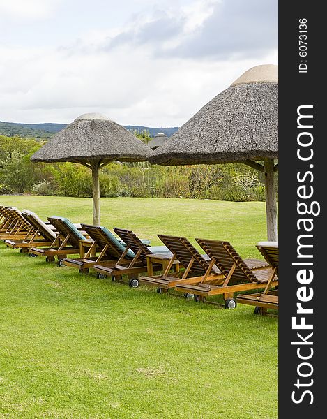 Beautiful lush garden on a farm in the countryside. Some deck-chairs are set on grass near a swimming pool. Beautiful lush garden on a farm in the countryside. Some deck-chairs are set on grass near a swimming pool.