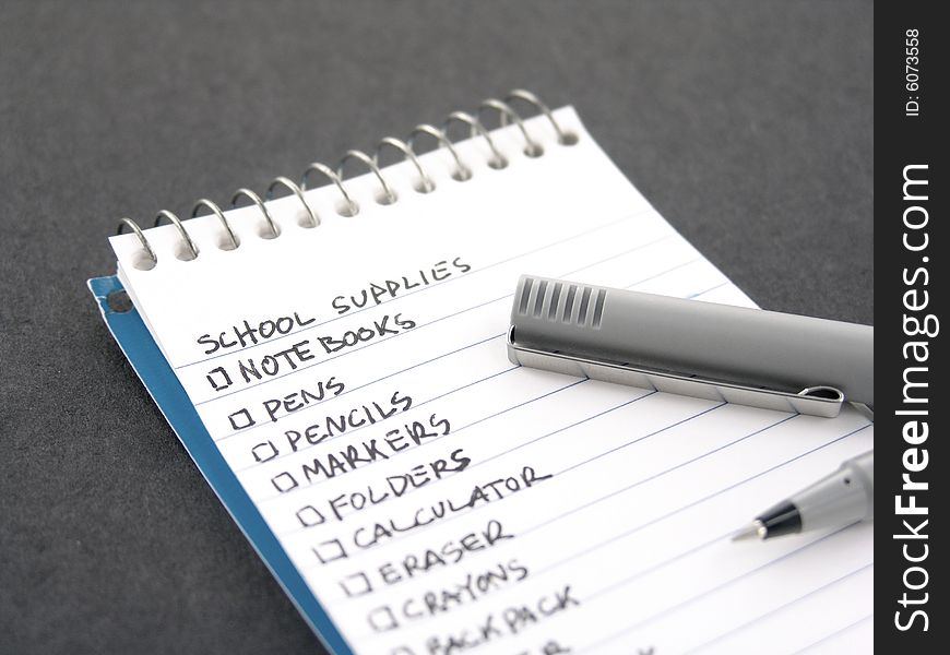 Check list for school supplies in notebook with pen. Check list for school supplies in notebook with pen