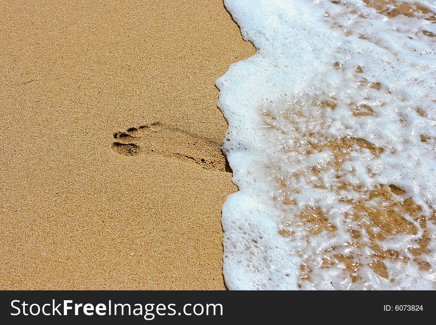 Footprint on sand and sea foam. Footprint on sand and sea foam