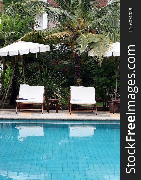 Deck chairs and umbrellas next to a swimming pool.