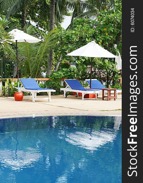 Deck chairs and umbrellas next to a swimming pool.