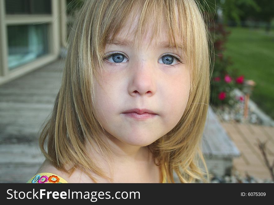 Head shot of little girl sitting outdoors with thoughtful look on face. Head shot of little girl sitting outdoors with thoughtful look on face