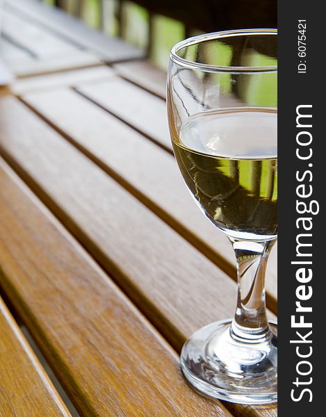 Glasses of white wine on a wooden table at an outside restaurant on a cloudy day in the countryside. Glasses of white wine on a wooden table at an outside restaurant on a cloudy day in the countryside.