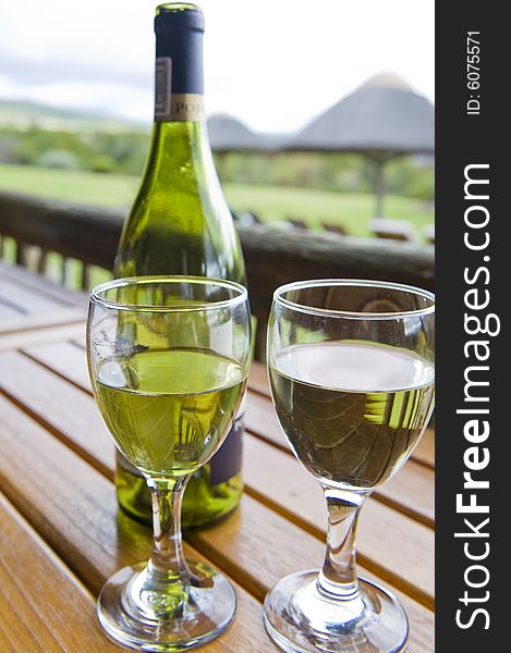 Glasses of white wine on a wooden table at an outside restaurant on a cloudy day in the countryside. Glasses of white wine on a wooden table at an outside restaurant on a cloudy day in the countryside.
