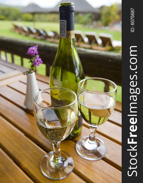 Glasses of white wine on a wooden table at an outside restaurant on a cloudy day in the countryside. Glasses of white wine on a wooden table at an outside restaurant on a cloudy day in the countryside.