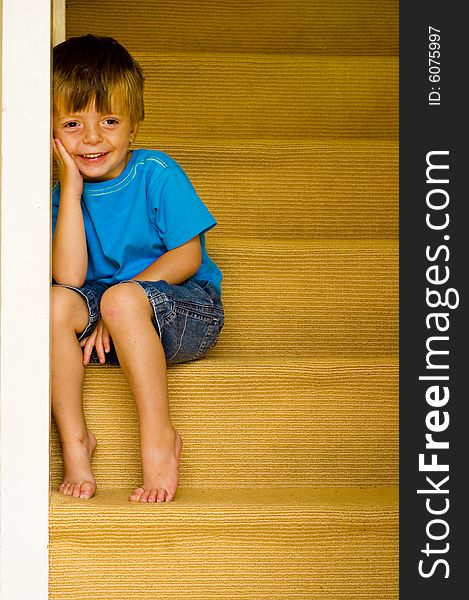 Happy Little Boy sitting on the stairs. Some copyspace to the right.