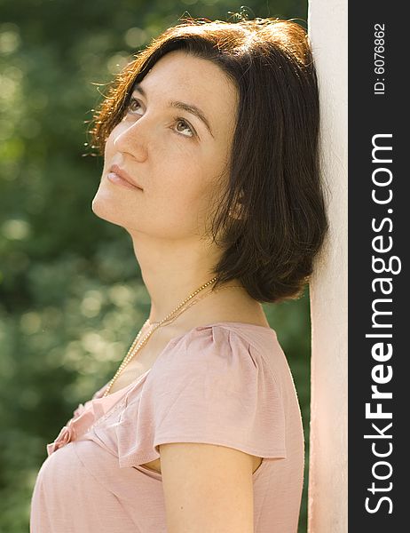 Portrait of dreaming pretty woman standing near white column