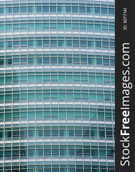 Full frame of a modern office building with transparent greenish windows.