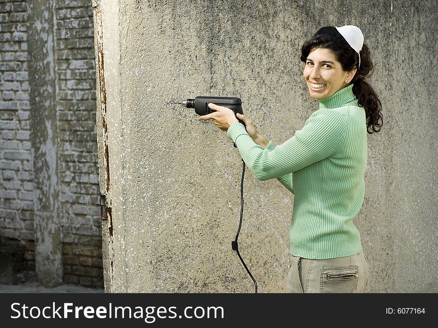 Smiling woman wearing with a mask on her head holding a drill. Horizontally framed photo. Smiling woman wearing with a mask on her head holding a drill. Horizontally framed photo.