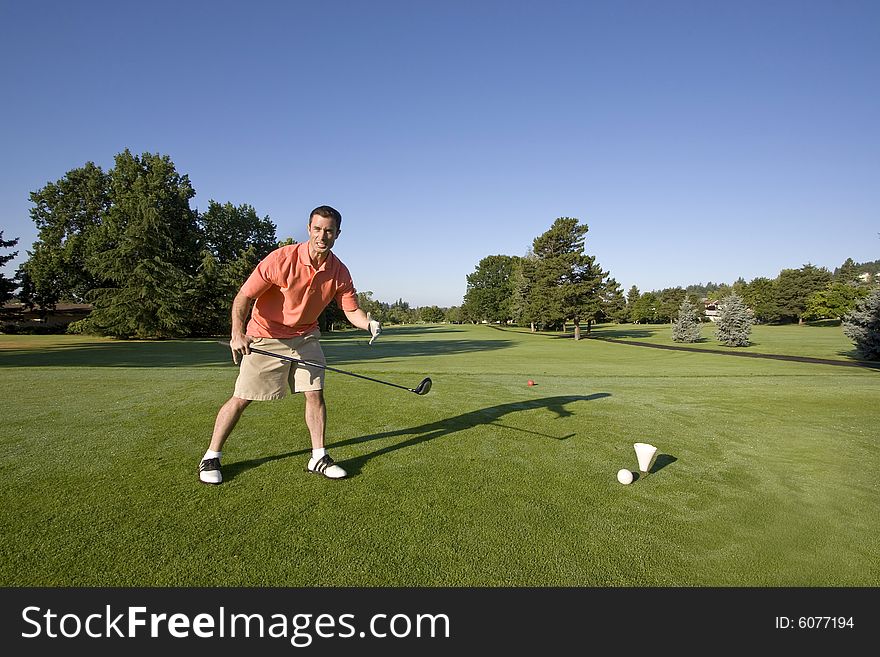 A man is standing on a golf course. He is holding a golf club and is looking angrily at the camera. Horizontally framed shot. A man is standing on a golf course. He is holding a golf club and is looking angrily at the camera. Horizontally framed shot.